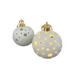 Cette Boule de noël photophore de 7 cm en porcelaine blanche est équipée d'un mécanisme de lumière et livrée avec piles.